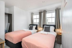 two beds in a small room with windows at Cosy and Functional 1 bedroom flat in London in London