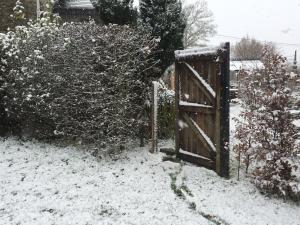 um portão aberto num quintal coberto de neve em Gîtanneke em Burg-Reuland