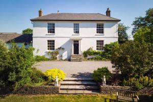 a large white house with a staircase in front of it at Enchanted Retreats at West Ford Devon in South Molton