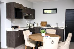 una pequeña cocina con mesa de madera y sillas en “Pop Inn” modern apartment in heart of Bryanston, en Johannesburgo