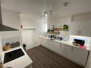 a large white kitchen with white cabinets and wooden floors at Central Falmouth with parking & courtyard in Falmouth