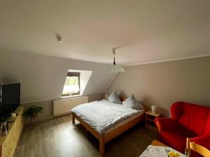 - une chambre avec un lit et une chaise rouge dans l'établissement Pension Riegler, à Nossen