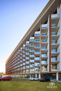 un grande edificio con auto parcheggiate in un parcheggio di Apartament Baltic Dune z dostępem do basenów,jacuzzi,strefy saun - Pinea Apartments Pobierowo-SANNEL Apartments for rent a Pobierowo