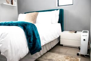 a bedroom with a bed with a blue blanket on it at “Pop Inn” modern apartment in heart of Bryanston in Johannesburg