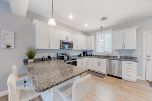 cocina con armarios blancos y encimera de granito en Cape Arundel House, en Kennebunk