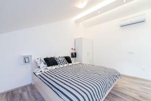ein weißes Schlafzimmer mit einem großen Bett mit schwarzen und weißen Streifen in der Unterkunft Bovolini's Place in Dubrovnik