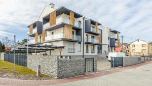 a building on a street with a stone wall at Apartamenty Sun & Snow Bursztynowa in Kąty Rybackie