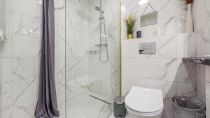 a white bathroom with a shower and a toilet at Apartamenty Sun & Snow Bursztynowa in Kąty Rybackie
