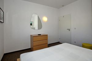 a bedroom with a bed and a dresser and a mirror at Macoma Baltica Wohnung 04 in Kühlungsborn