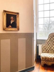 una pintura de una mujer en una pared junto a una silla en Landhotel Schloss Daschow en Daschow