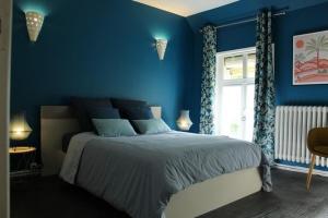 Dormitorio azul con cama y ventana en Gîte La Riviera, en Wargnies-le-Grand