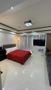 een slaapkamer met een rood bed en een flatscreen-tv bij Condo Unit Near Terminal 3 in Manilla