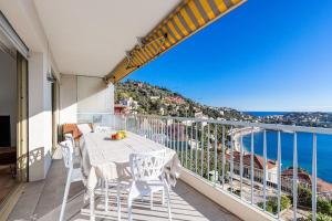 een balkon met een tafel en stoelen en de oceaan bij Villefranche Sur Mer:Appartement-villa, Vue mer, jardin, parking. in Villefranche-sur-Mer