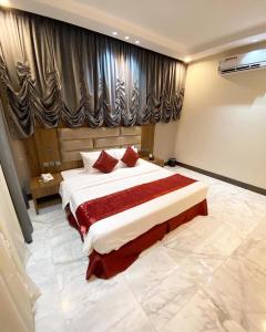 a bedroom with a large bed with red pillows at الروض للشقق المفروشه خاصة in Al Madinah