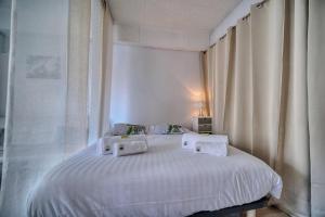 a bedroom with a white bed with white sheets and pillows at IMMOGROOM - Near the city centre and the beach - Air conditioning - Terrace in Cannes