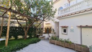 une cour avec un arbre et un bâtiment blanc dans l'établissement MARILISE - La maison bleue private hot tube, garden & terrace, à Meta