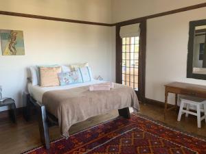 een slaapkamer met een bed, een tafel en een spiegel bij Karoo Soul in Oudtshoorn