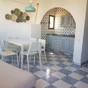 a dining room with a table and chairs and a kitchen at Formentera Es Pujols 2 camere vicinissimo alla spiaggia in Es Pujols
