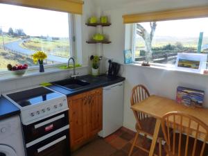 cocina con fogones, fregadero y mesa en Crepigill Cottage, en Portree