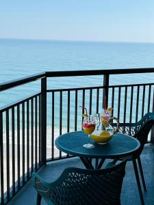 a table with two wine glasses on a balcony with the ocean at 1602 Coastal Soul Pet friendly in Myrtle Beach