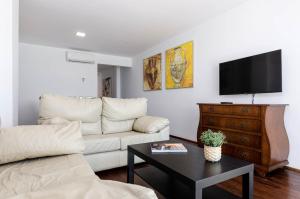 ein Wohnzimmer mit einem weißen Sofa und einem Fernseher in der Unterkunft YourHouse BlauBlue 2 1, sea view apartment in Can Picafort