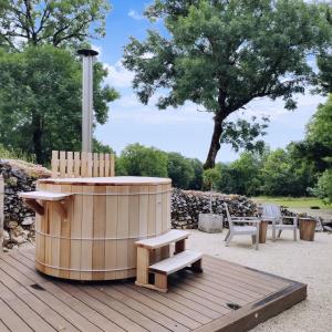 una terraza de madera con bañera de hidromasaje y banco en Manoir de Malagorse en Cuzance