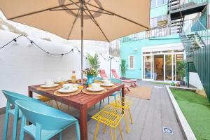 un patio con mesa de madera, sillas y sombrilla en Charming 3BR APT w/ patio, by TimeCooler en Lisboa