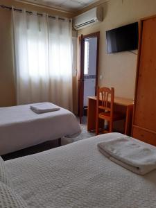 a hotel room with two beds and a desk and a chair at Alojamiento Mª Carmen in El Real de la Jara