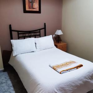 1 dormitorio con 1 cama grande con sábanas y almohadas blancas en Alojamiento Mª Carmen, en El Real de la Jara