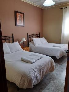 um quarto com 2 camas e lençóis brancos em Alojamiento Mª Carmen em El Real de la Jara