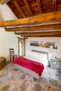 a bedroom with a large bed with a red blanket at Agriturismo Valliera in Castelmagno