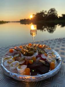 a plate of food on a table with a wine glass at White Sands Lodge in Divundu