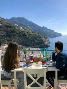 a man and woman sitting at a table overlooking the ocean at Filù Rooms Paradise Tower in Minori