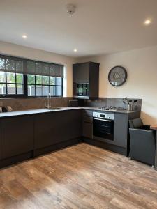 a kitchen with black cabinets and a wooden floor at Booking Urban Halstead in Halstead