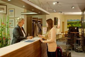 deux femmes debout à un comptoir dans un magasin dans l'établissement Waldhotel Felschbachhof, à Ulmet