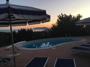 ein Pool mit einem Sonnenschirm, einigen Stühlen und einem Sonnenschirm in der Unterkunft Villa "Ai Galli" in Terracina