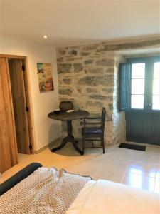 una camera da letto con un tavolo e una sedia accanto a un muro di pietra di PausaSTAY - QdM Artist Suites - Villa a Alvorge