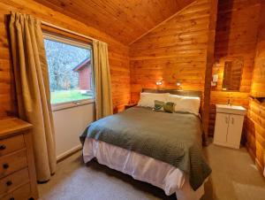 1 dormitorio con 1 cama en una cabaña de madera en Ruskin Lodges Argyll, by Puck's Glen, Rashfield near Dunoon, en Dunoon