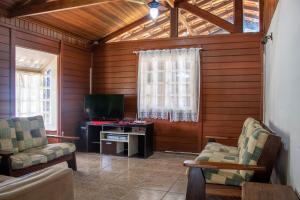 sala de estar con 2 sillas y TV en Casa de campo c piscina e churrasq em Mairipora SP, en Mairiporã