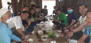 Eine Gruppe von Menschen, die an einem Tisch sitzen und Essen essen. in der Unterkunft Homestay Nguyễn Huệ in Làng Mõ