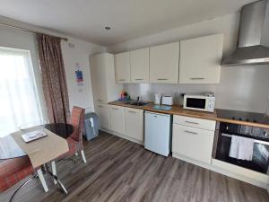 a kitchen with white cabinets and a table and a microwave at Dainville Retreat in Skegness