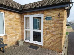 a brick building with a white door and a bench at Dainville Retreat in Skegness