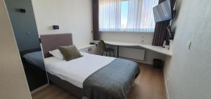 a small room with a bed and a desk with a window at Hotel du Bassin in Ostend