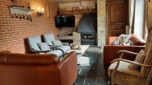 uma sala de estar com sofás e uma lareira de tijolos em Gîte l'Amandina - Porcheresse em Daverdisse