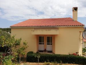 a small yellow house with a red roof at Apartments Marijan - sea view in Veli Rat