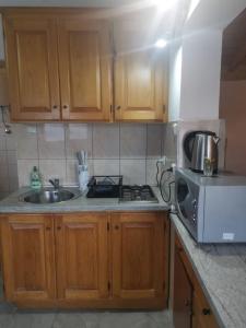 a kitchen with wooden cabinets and a sink and a microwave at Apartments More - sea front in Savar