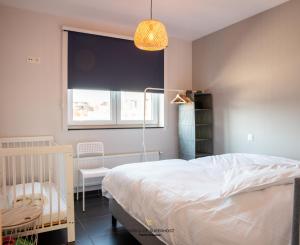1 dormitorio con cama, ventana y cuna en New modern apartment near the sea and city centre, en Ostende