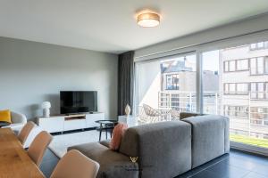 sala de estar con sofá y ventana grande en New modern apartment near the sea and city centre, en Ostende