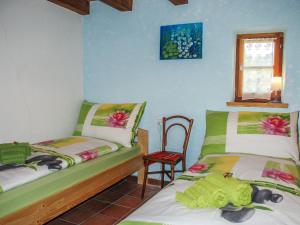 1 dormitorio con 2 camas, silla y ventana en Holiday Home Rustico Fey by Interhome, en Malvaglia
