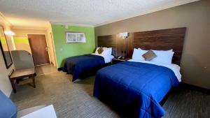 una camera d'albergo con due letti con lenzuola blu di The Lincoln Hotel Philadelphia a Trevose